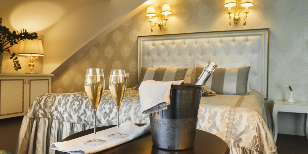 Two glasses of and champagne in ice bucket in luxury hotel. Romance, room service, relax concept, copy space